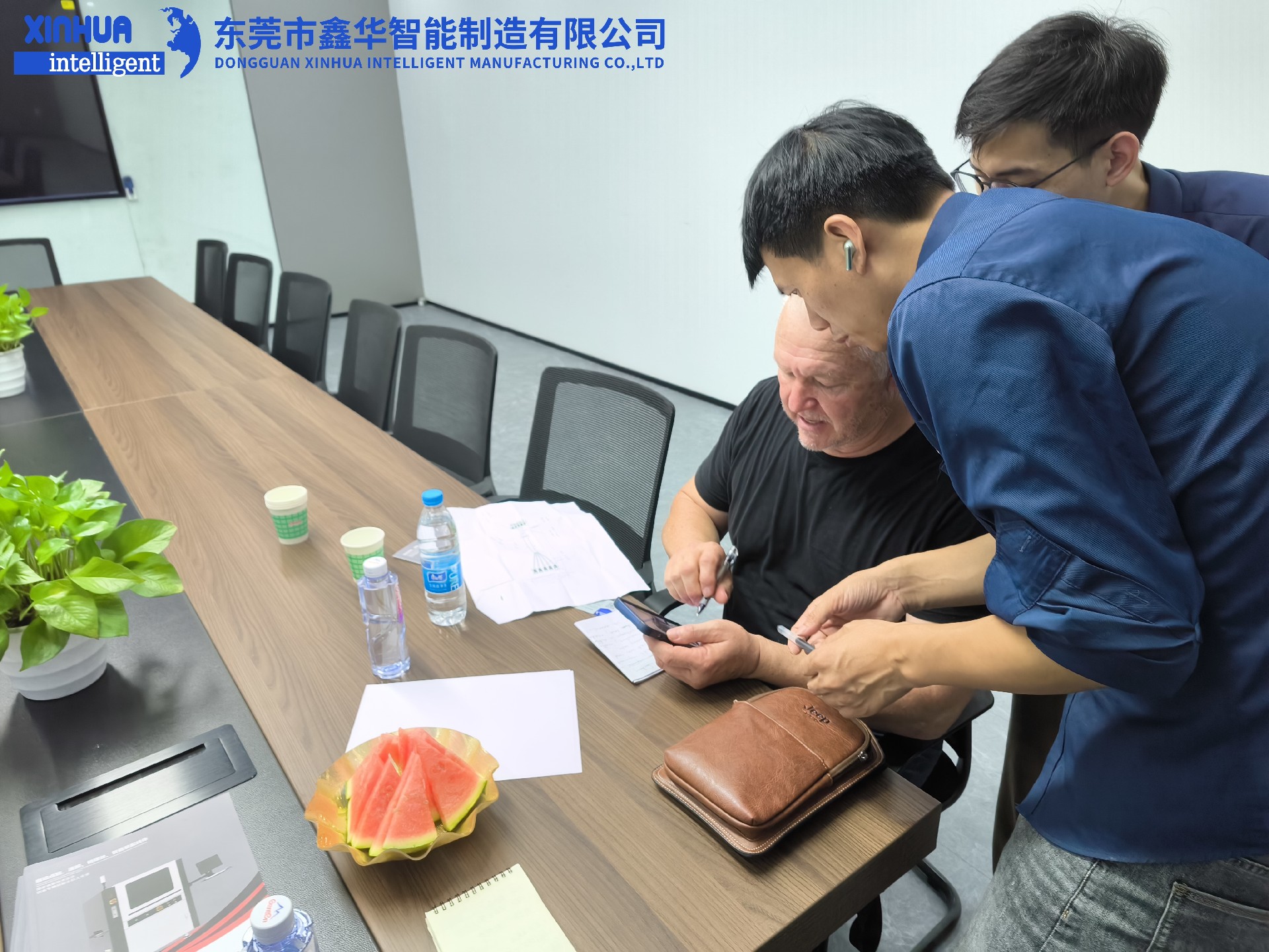 业务部2位男同事在给美国客户耐心介绍自动锁螺丝机性能